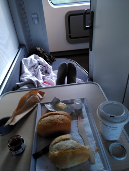 A view of the sleeping compartment. There's a tray with breakfast, two rolls and coffee