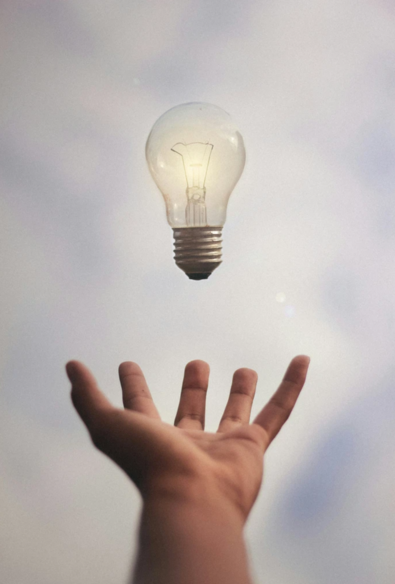a lit bulb hovering above an open hand