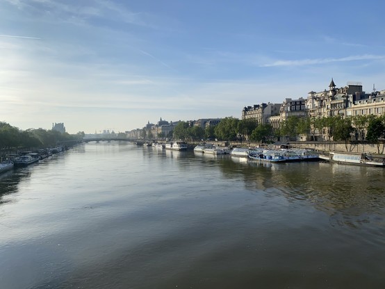 View over the Seine river upstream. Classical buildings, I don’t know and some moored boats on the left Riverbank. 
