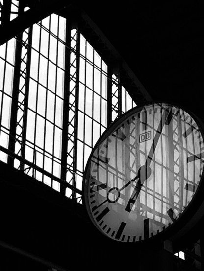 Schwarzweißfotografie einer Bahnhofsuhr vor einem Fenster