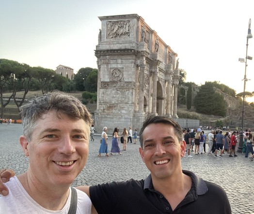 Two people standing in front of an arch- the Arch of Titus (?)