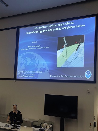 Woman stands in front of a title slide with an image of the earth from.space